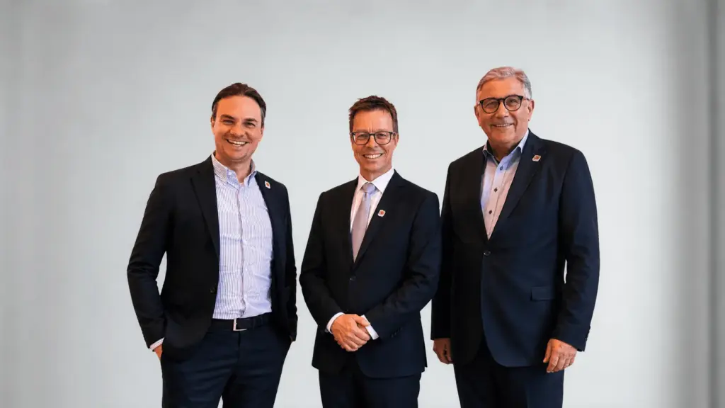 Drei Männer in dunklen Anzügen posieren lächelnd nebeneinander vor hellem Hintergrund – FDP-Stadtratsfraktion Passau