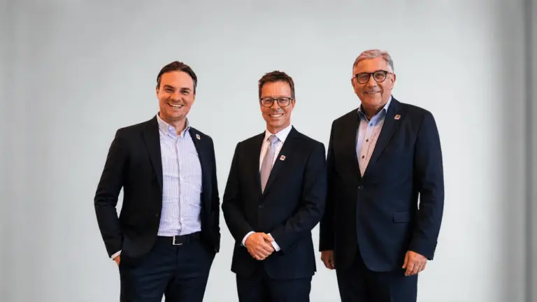 Drei Männer in dunklen Anzügen posieren lächelnd nebeneinander vor hellem Hintergrund – FDP-Stadtratsfraktion Passau
